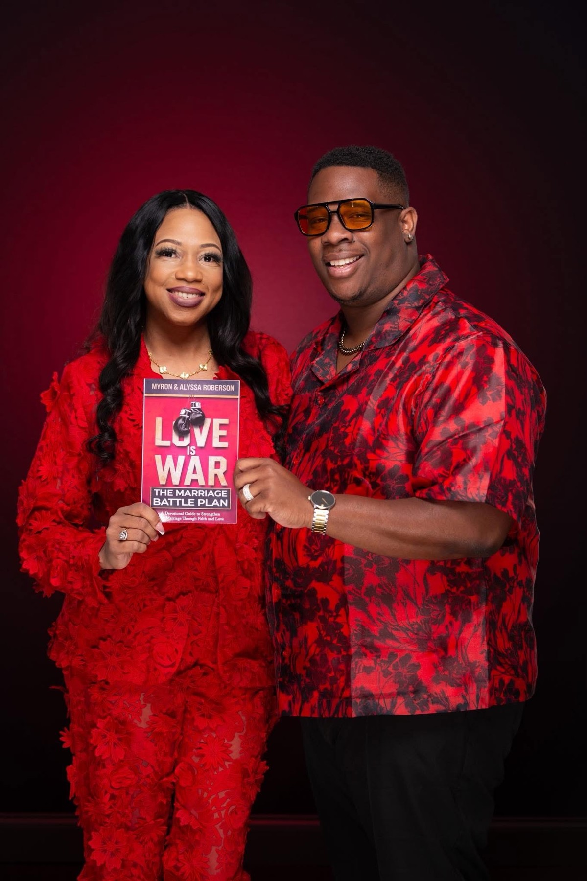 Alyssa and Myron Roberson holding their book Love Is War
